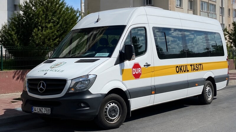 Minibus scolaire blanc portant le panneau « véhicule scolaire »